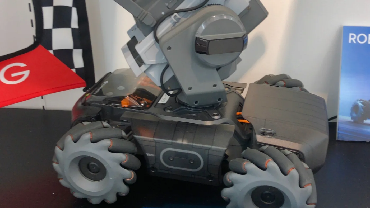 Side view of a real RoboMaster S1 showing its four mecanum wheels and the camera mounted on the gimbal